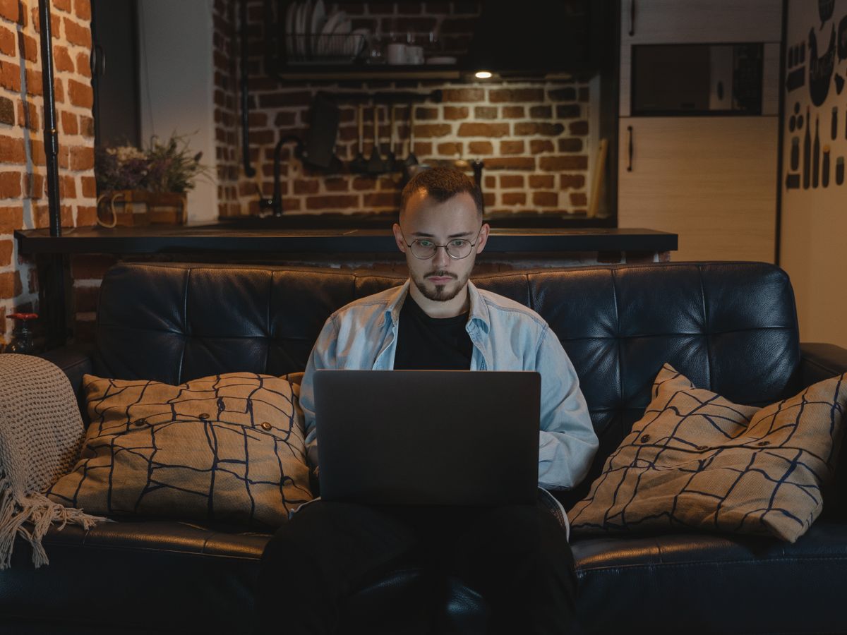 Homem trabalhando remotamente em um laptop em casa.